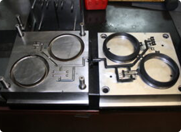 Two metal molds with circular cavities on a workbench.